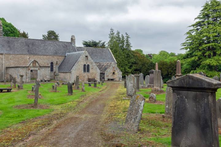 a stone church with a path and grass in front of a house