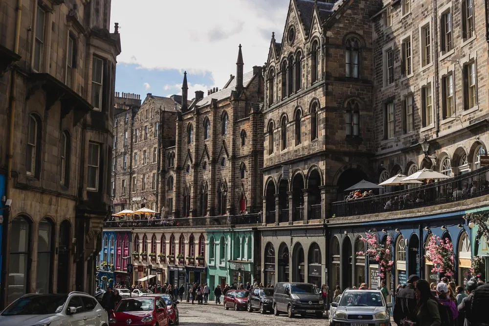 Street with historic stone buildings, colorful storefronts, and people walking and dining outdoors.